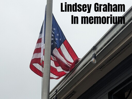 A water soaked American flag, at half-mast, but it's also draped into the rain gutter of the adjacent roof. 